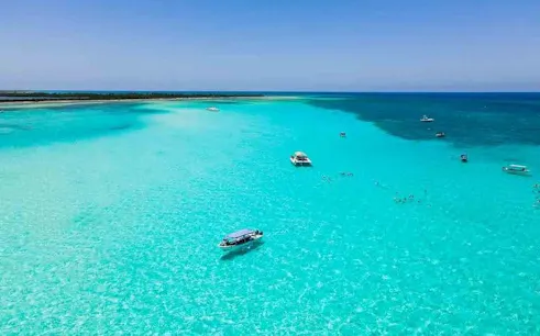 Cozumel El Cielo turquoise waters with boats and snorkelers exploring reefs.