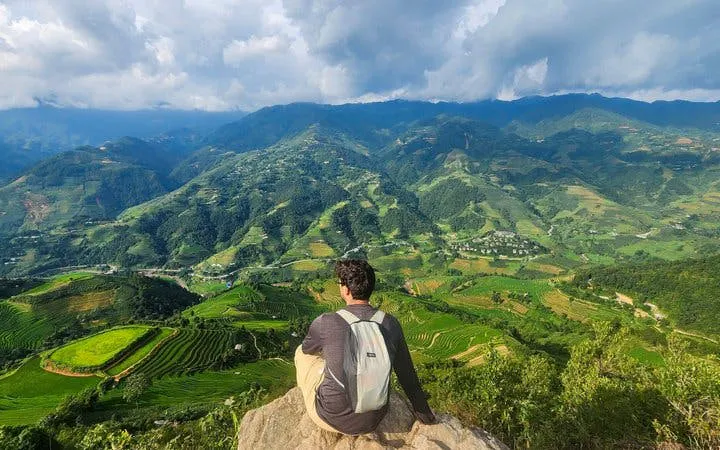Traveler overlooking terraced rice fields in Mu Cang Chai during trekking tour.