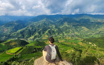 Traveler overlooking terraced rice fields in Mu Cang Chai during trekking tour.