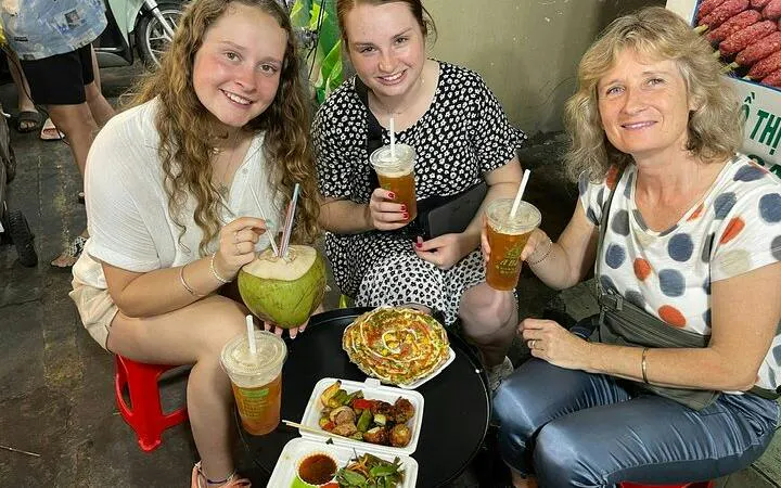 Tourists enjoying street food and drinks on a motorbike tour in Ho Chi Minh City's back alleys.