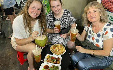 Tourists enjoying street food and drinks on a motorbike tour in Ho Chi Minh City's back alleys.