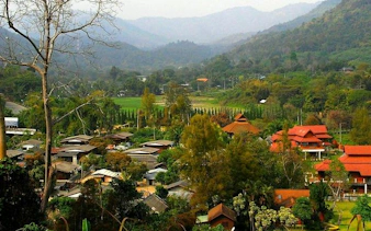 Mae Kham Pong Village nestled in lush hills, Chiang Mai, showcasing traditional Thai architecture.