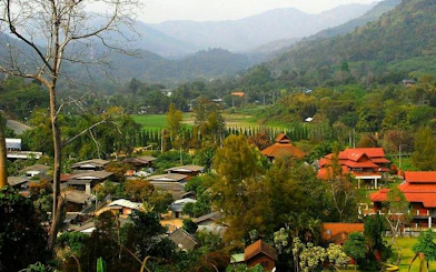 Mae Kham Pong Village nestled in lush hills, Chiang Mai, showcasing traditional Thai architecture.