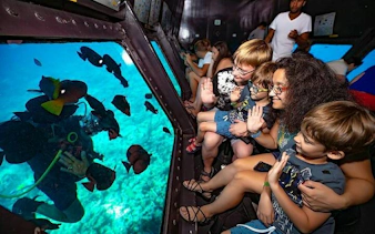 Visitors observing fish through submarine windows on a sea trip in Hurghada.