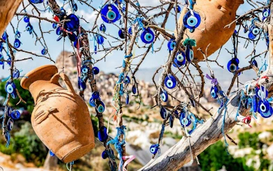 Cappadocia tree adorned with blue evil eye charms and clay pots.