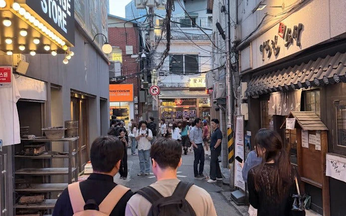 Seoul street with people exploring Chimaek night food spots, featuring fried chicken and beer venues.