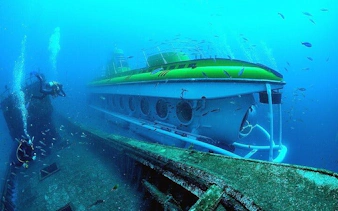 Submarine exploring underwater near shipwreck in Tenerife.