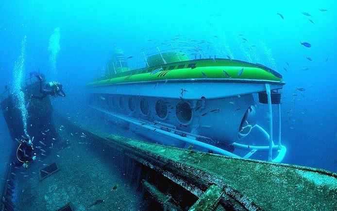 Submarine exploring underwater near shipwreck in Tenerife.