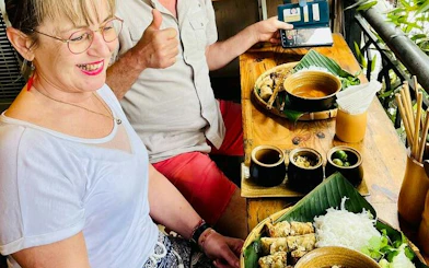 Tourists enjoying traditional Vietnamese meal on Hanoi countryside Vespa tour.