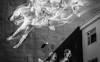 Street art mural of horses and figures on a building wall in Reykjavik alley.