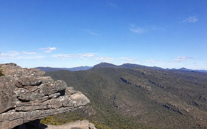 Grampians National Park rocky cliff with expansive forested mountain view.