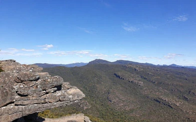 Grampians National Park rocky cliff with expansive forested mountain view.
