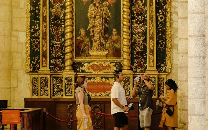 Tourists exploring a historic church interior in Santo Domingo with ornate artwork.