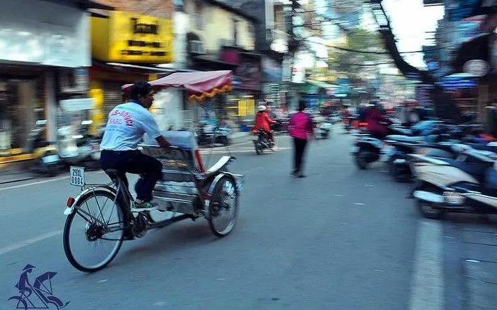Cyclo navigating Hanoi's Old Quarter street, showcasing local shops and bustling activity.