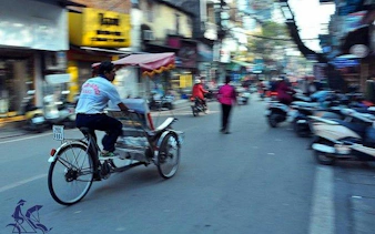 Cyclo navigating Hanoi's Old Quarter street, showcasing local shops and bustling activity.