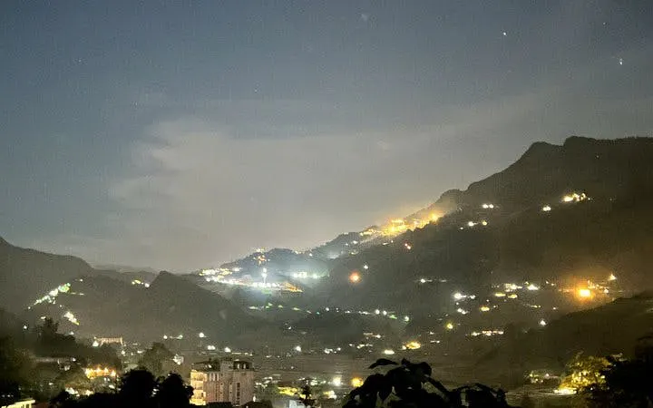 Sapa valley at sunset with illuminated hills and distant Giay stilt houses.