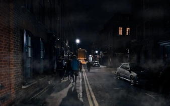 Walking tour group on a foggy London street at night, exploring Jack the Ripper sites.