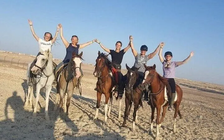 Horseback riders holding hands on a sandy beach near the Red Sea, Hurghada.