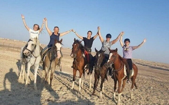 Horseback riders holding hands on a sandy beach near the Red Sea, Hurghada.