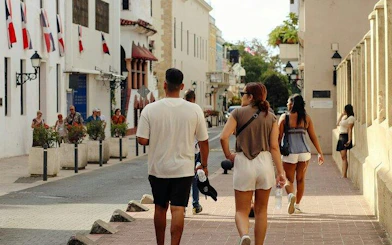 Tourists walking in Santo Domingo Colonial Zone with historic buildings and flags.