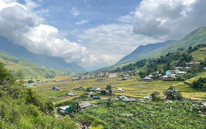Sa Pa valley view with terraced fields and village houses under cloudy sky.