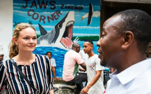 Stone Town tour guide and visitor at Jaws Corner mural, Zanzibar.