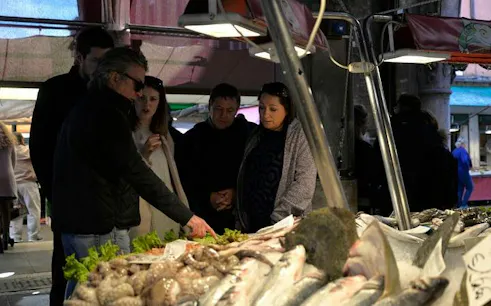 Tour group exploring seafood at Rialto Market, Venice.