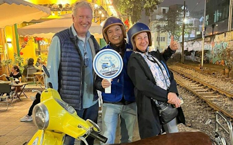Vespa riders enjoying Hanoi street food tour by train tracks at night.