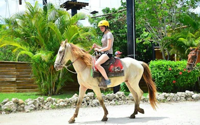 Horseback rider on a trail in Punta Cana with lush greenery in the background.