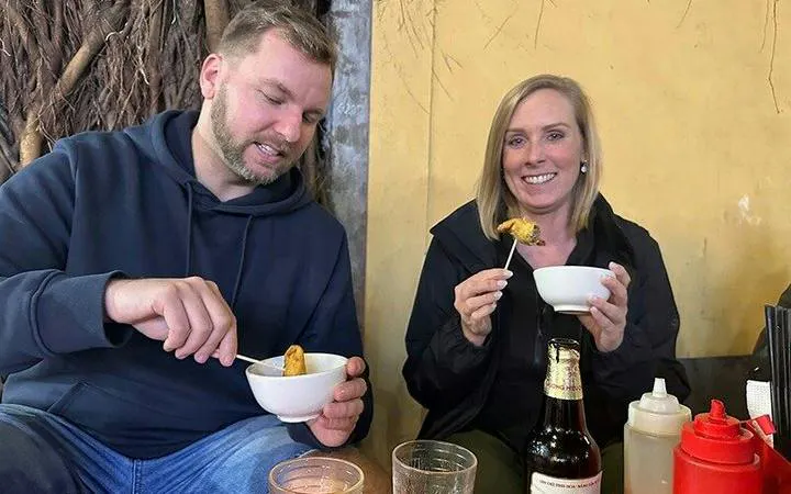 Tourists enjoying street food during Hanoi Old Quarter cyclo tour.