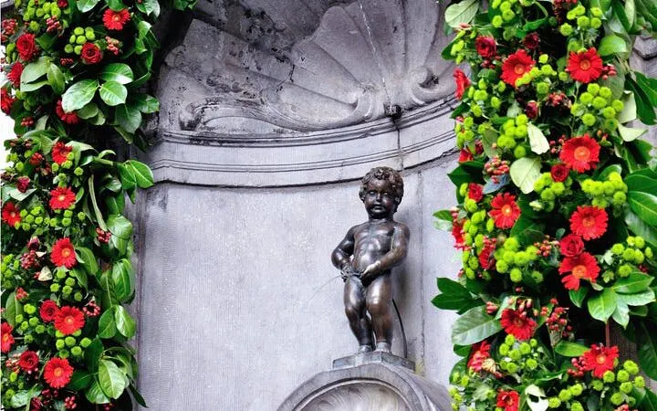 Manneken Pis statue in Brussels adorned with floral decorations.