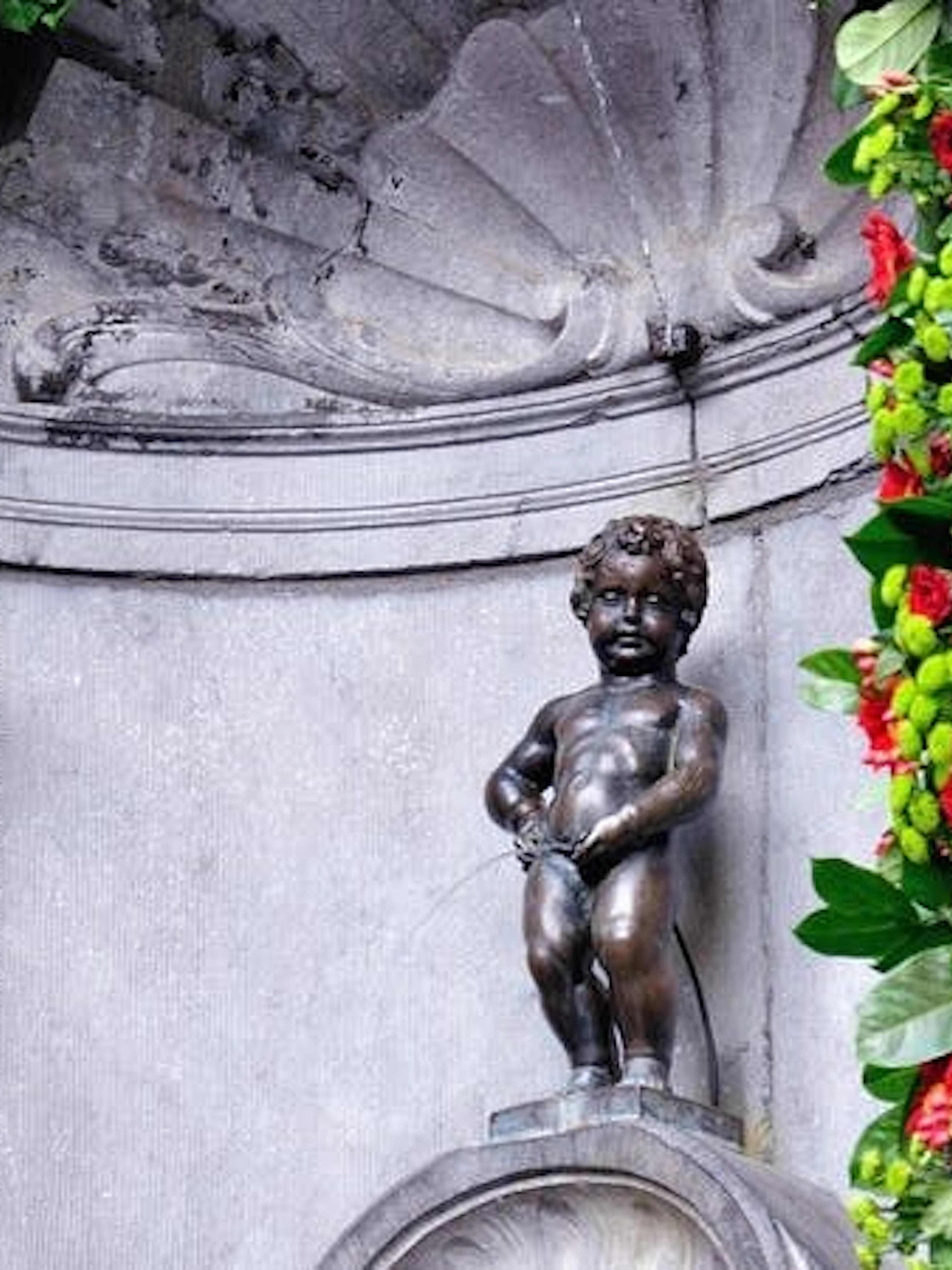 Manneken Pis statue in Brussels adorned with floral decorations.
