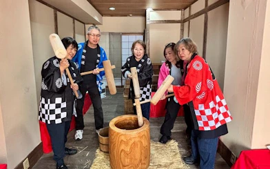 Group participating in traditional mochi pounding in Japan, wearing colorful costumes.