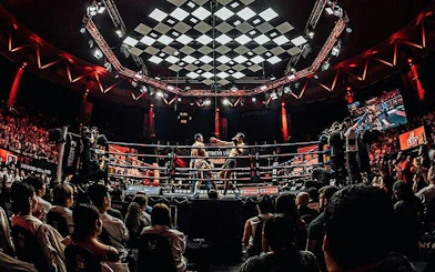 Muay Thai match at Rajadamnern Stadium, Bangkok with audience and photographers ringside.