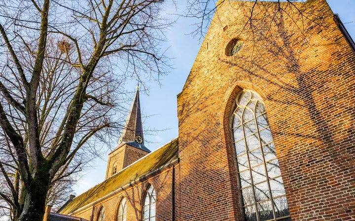 Utrecht church with brick facade and tall spire, part of city exploration game.