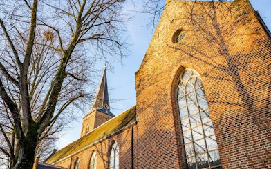 Utrecht church with brick facade and tall spire, part of city exploration game.