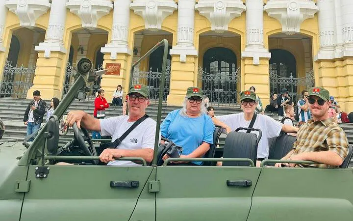 Tourists in a jeep in front of Hanoi Opera House during city tour.