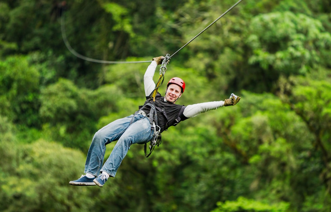 Visitors ziplining through lush forest.