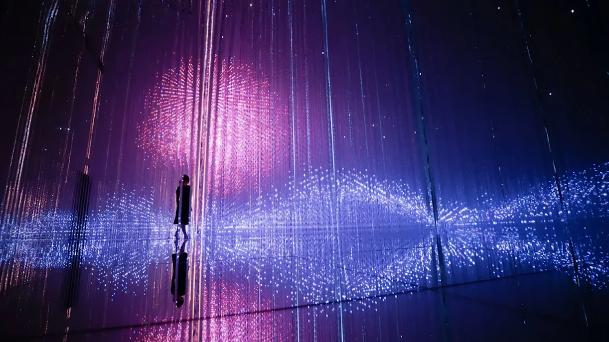 Interactive light installation at TeamLab Planets Tokyo with person silhouetted against colorful lights.