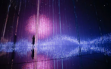 Interactive light installation at TeamLab Planets Tokyo with person silhouetted against colorful lights.