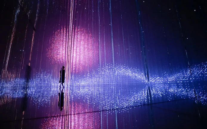 Interactive light installation at TeamLab Planets Tokyo with person silhouetted against colorful lights.