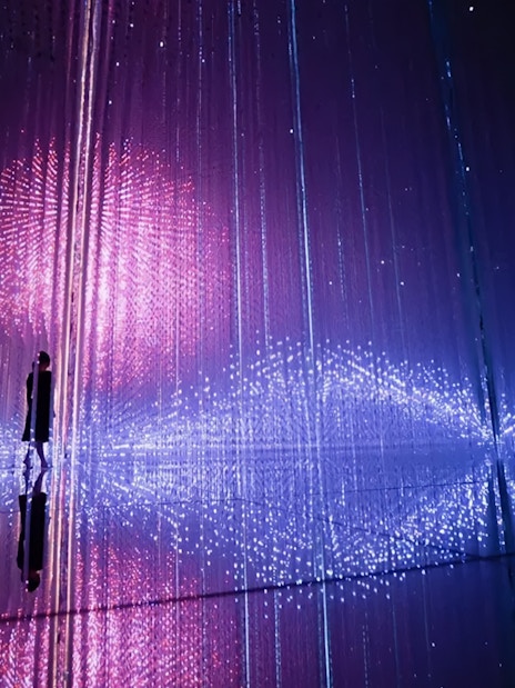 Interactive light installation at TeamLab Planets Tokyo with person silhouetted against colorful lights.