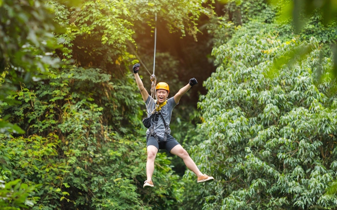 Tourist ziplining through lush green forest near Phuket.