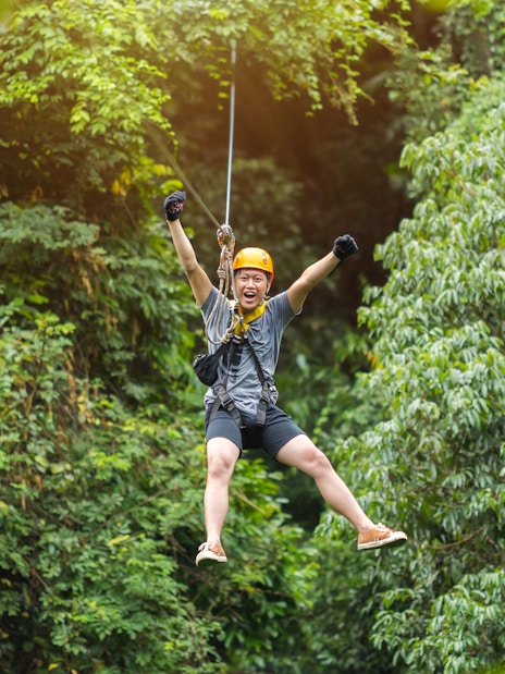 Tourist ziplining through lush green forest near Phuket.