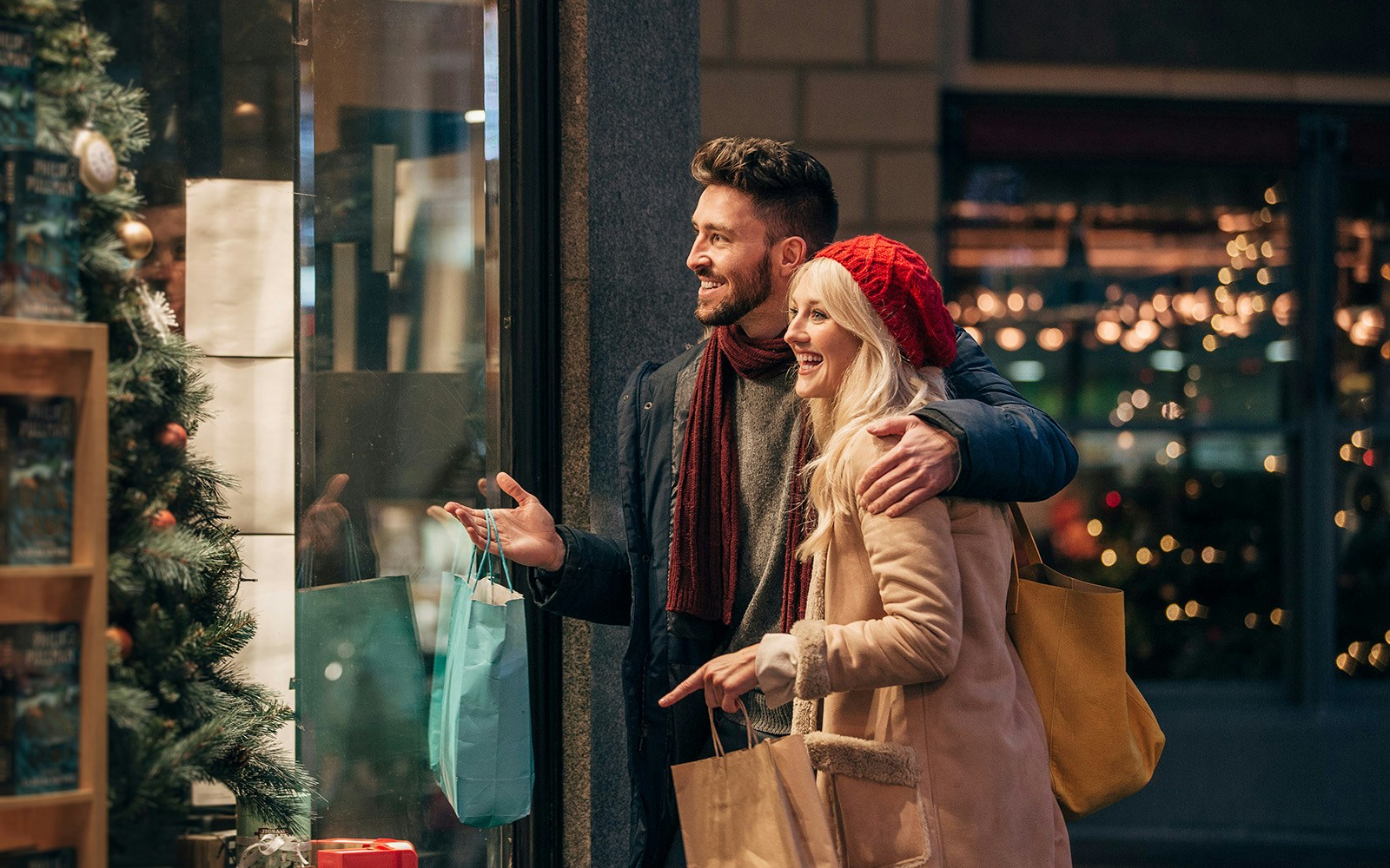 Couple shopping during Christmas in Melbourne, admiring festive window displays.