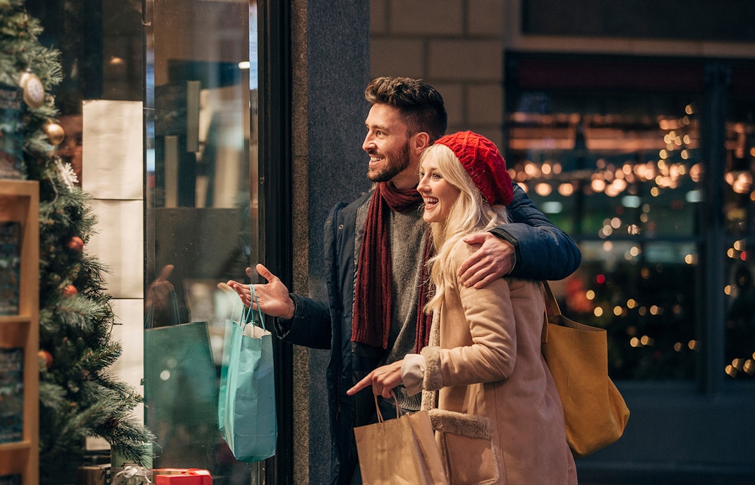 Couple shopping during Christmas in Melbourne, admiring festive window displays.