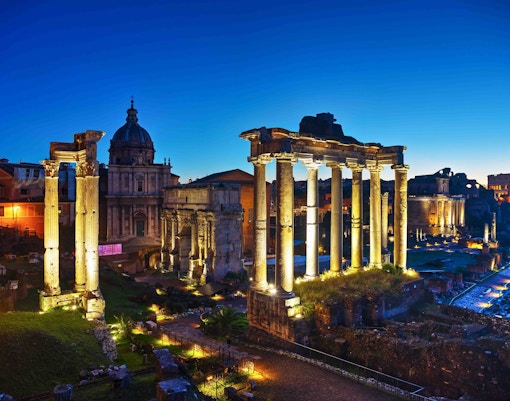 Roman Forum ruins illuminated at night, with Colosseum night tours in Rome, Italy.