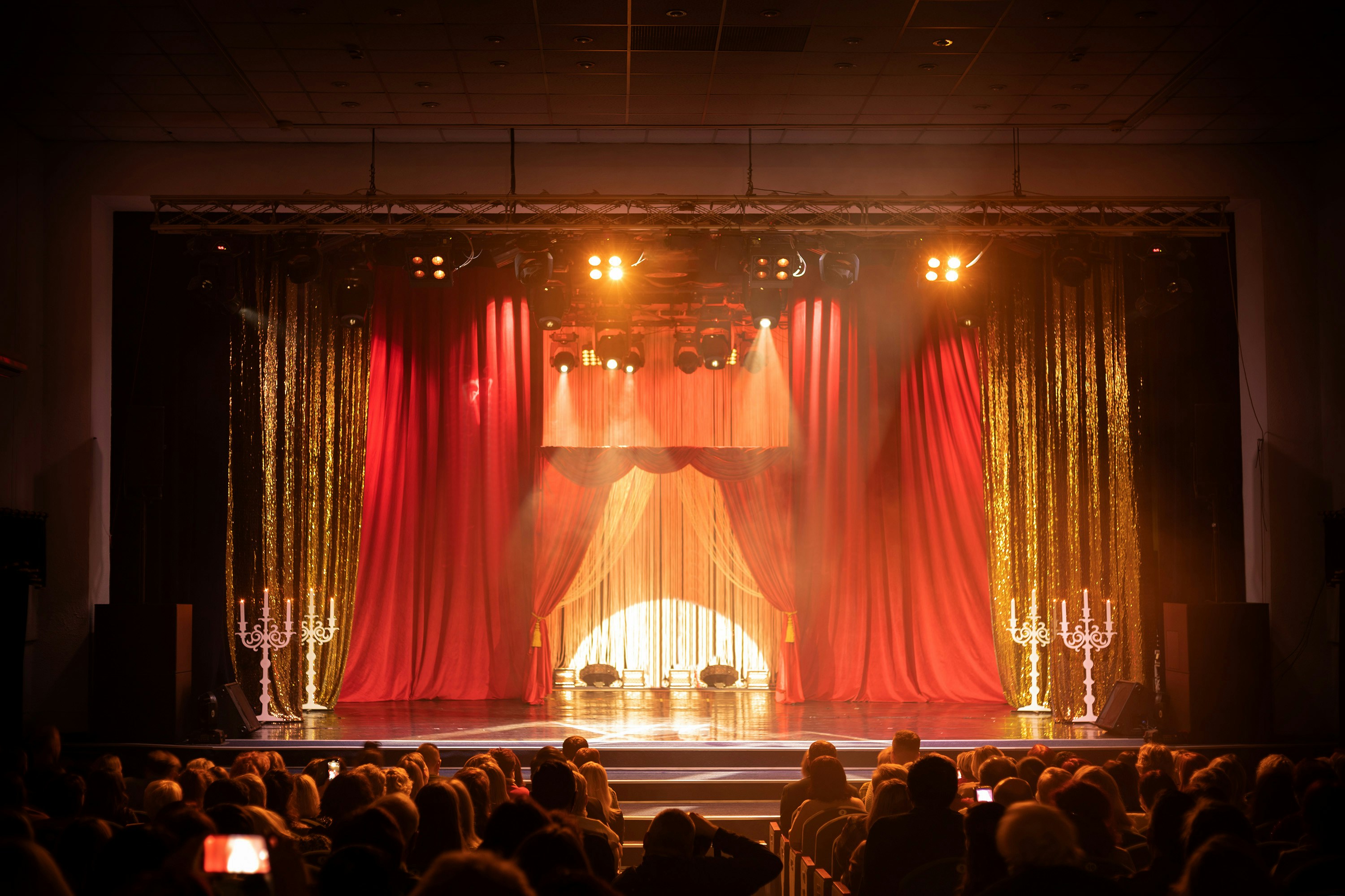 Stage with red curtains and candelabras in a Milan theater during a Christmas music event.