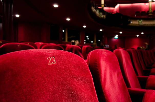 Red velvet seats in a London theatre, highlighting seat number 23.