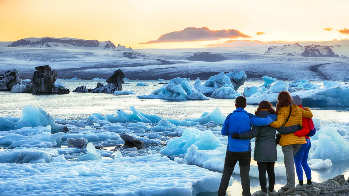 Tourists admiring icebergs at Jokulsarlon Glacier Lagoon during ice caving tour.